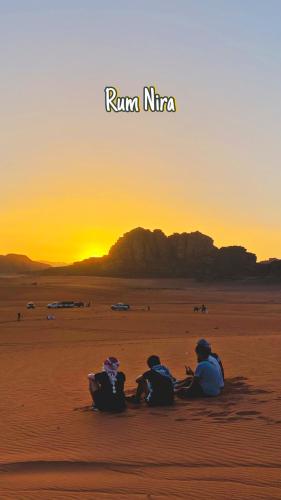 three people sitting in the desert watching the sunset at Wadi Rum Luxure desert Camp in Wadi Rum