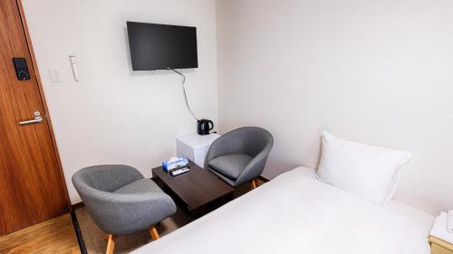 a hotel room with two chairs and a bed and a tv at Ayanishiki大阪西九条STAY in Osaka