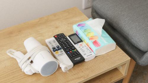 a coffee table with remote controls and shoes on it at Ayanishiki大阪西九条STAY in Osaka