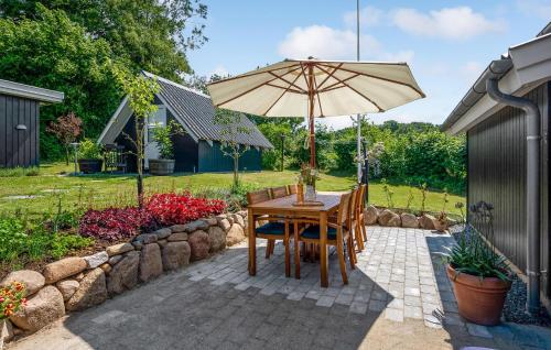 une table et des chaises avec un parasol sur une terrasse dans l'établissement Holiday Home Træløbervej Tranekær Ii, à Lokkeby