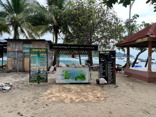 a kiosk on a beach with signs on it at Perhentian Mama's in Perhentian Island