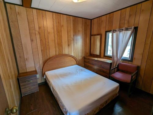 a bedroom with a bed and a desk and a window at Tiny Wood Cottage 07 in Wasaga Beach