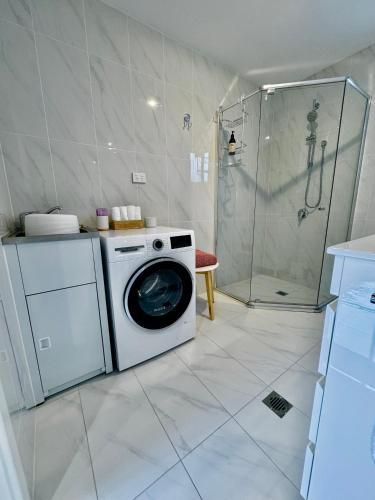 a washing machine in a bathroom with a shower at Seaside Cottage in Curl Curl