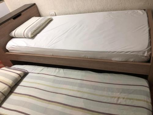 a bunk bed with white sheets and a striped rug at Apartaestudio cerca al Centro Comercial Fabricato in Bello