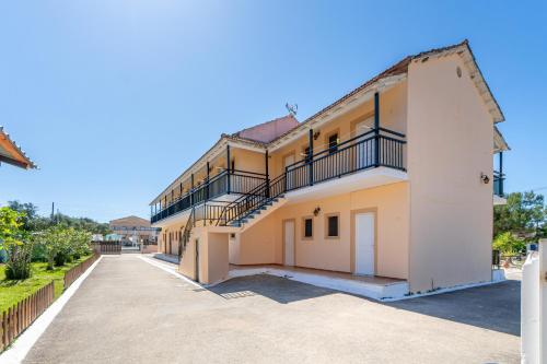 a large house with a balcony on the side at Sandy Beach Complex - Poolside Studios & Seaside Apartments in Kavos