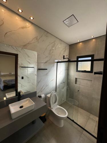 a bathroom with a toilet and a sink and a mirror at Chalés Varandas da Serra in Monte Verde