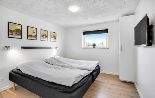 a bed in a white room with a flat screen tv at Four-Bedroom Holiday Home In Haderslev in Haderslev