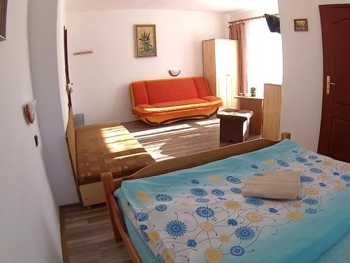 a bedroom with a bed and an orange chair at Privát Bayer in Ždiar