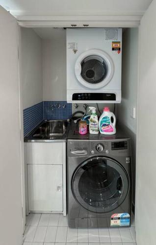 a small kitchen with a washing machine and a sink at Chic Modern Oasis - Steps from Darling Harbour in Sydney
