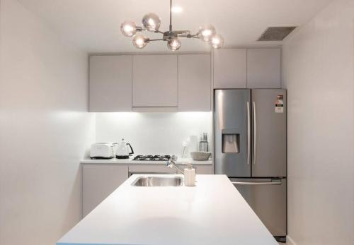 a white kitchen with a sink and a refrigerator at Chic Modern Oasis - Steps from Darling Harbour in Sydney
