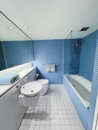 a blue tiled bathroom with a toilet and a sink at Chic Modern Oasis - Steps from Darling Harbour in Sydney