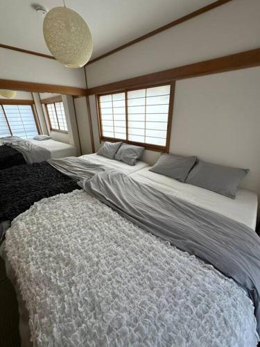 Un dormitorio con dos camas en una habitación con ventanas. en Style Labお花茶屋2, en Tokio
