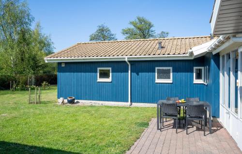 a blue house with a table and chairs in the yard at Nice Home In Skælskør With Sauna in Skælskør