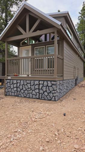 a house with a large porch and a stone wall at Cozy Cabins By Forest View 3B in Williams