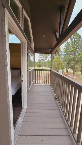 a porch of a house with a bed on it at Cozy Cabins By Forest View 3B in Williams