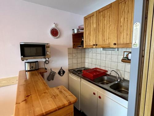 une petite cuisine avec un évier et un micro-ondes dans l'établissement Studio cosy avec terrasse ensoleillée - FR-1-787-26, à Laveissière