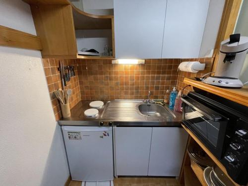 une petite cuisine avec un évier et un micro-ondes dans l'établissement Duplex au Lioran avec balcon, proche pistes et commerces - FR-1-787-25, à Laveissière