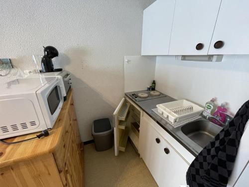 une petite cuisine avec un évier et un micro-ondes dans l'établissement Appartement T2 cabine avec balcon, face aux pistes, exposé sud, commerces à proximité - FR-1-787-29, à Laveissière