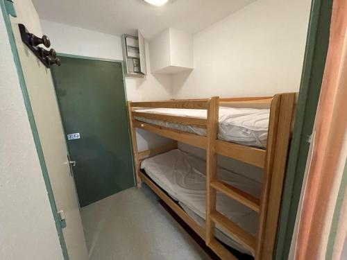 Cette petite chambre comprend des lits superposés et une porte. dans l'établissement Studio cosy à Laveissière près des pistes, 2 lits superposés et lit rabattable, parfait pour l'hiver - FR-1-787-8, à Laveissière