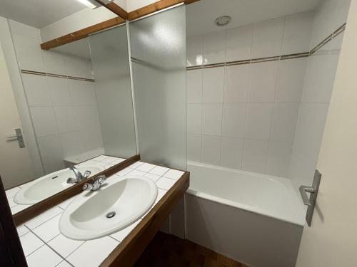 une salle de bain blanche avec un lavabo et une baignoire dans l'établissement Charmant studio avec balcon, au pied des pistes et commerces - FR-1-787-24, à Laveissière