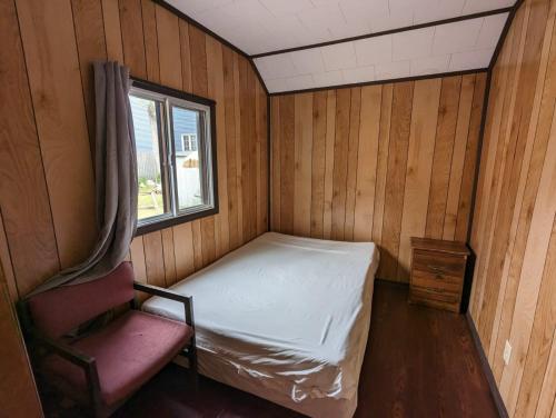 una piccola stanza con un letto e una sedia di Tiny Wood Cottage 10 a Wasaga Beach