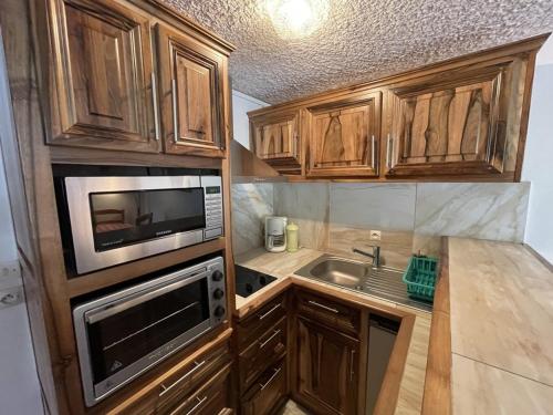 La cuisine est équipée de placards en bois, d'un four micro-ondes et d'un évier. dans l'établissement Studio-cabine cosy: au pied des pistes, balcon Sud-Est, commerces et patinoire à proximité - FR-1-787-42, à Laveissière
