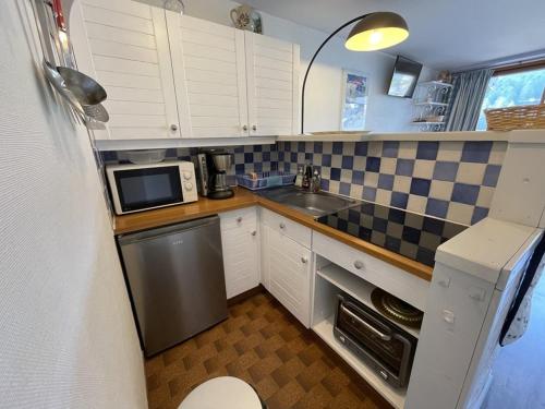 une petite cuisine avec un évier et un micro-ondes dans l'établissement Studio confortable avec balcon plein sud, à côté des pistes et commerces - FR-1-787-23, à Laveissière