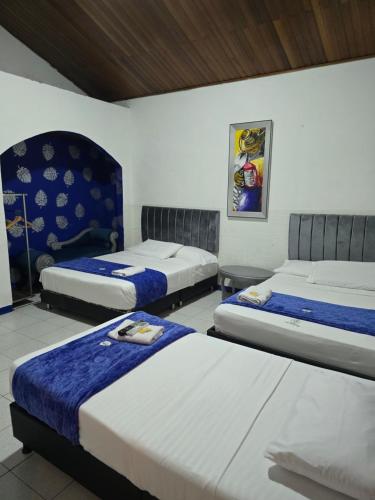 a room with three beds in a room at Casa Hotel Victoria Real in Mariquita