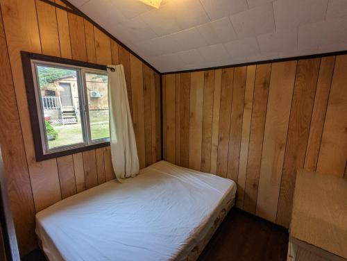 ein kleines Zimmer mit einem Bett und einem Fenster in der Unterkunft Tiny Wood Cottage 11 in Wasaga Beach