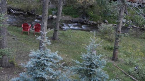 two red chairs in the woods next to a stream at Antlers Riverside Lodge in Red River