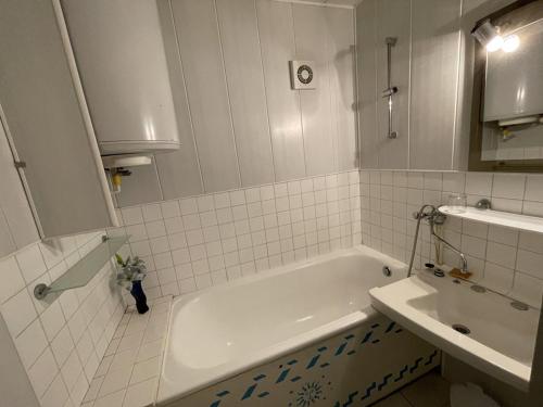 une salle de bain blanche avec une baignoire et un lavabo dans l'établissement Studio avec balcon en centre station, WiFi et animaux admis - FR-1-787-60, à Laveissière