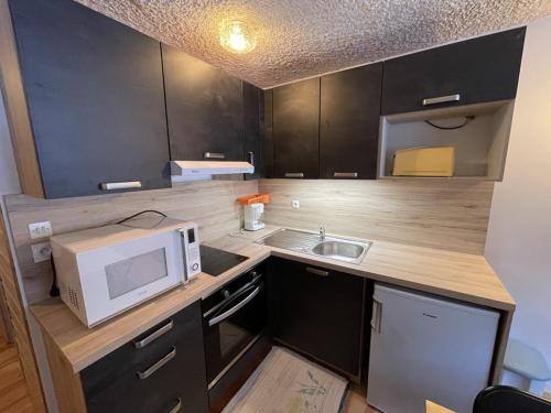 une petite cuisine avec un micro-ondes et un évier dans l'établissement Charmant Studio Rénové au Pied des Pistes avec Casier à Skis - FR-1-787-47, à Laveissière