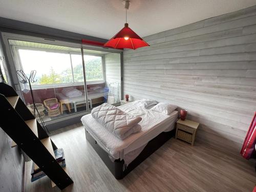 ein Schlafzimmer mit einem Bett und einem großen Fenster in der Unterkunft Appartement T2 cabine avec balcon, accès piste, parking, animaux bienvenus - FR-1-787-69 in Laveissière