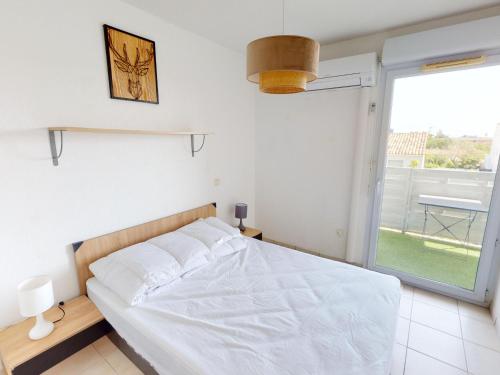 una camera da letto con un letto bianco e una grande finestra di Appartement de charme avec piscine, terrasse, parking, clim et Wi-Fi – à 10 min des plages - FR-1-785-2 a Frontignan
