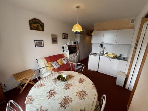 une cuisine et une table dans une pièce avec une table et une cuisine dans l'établissement Charmant T2 près des pistes avec équipement bébé, casier à skis, animaux non admis - FR-1-787-68, à Laveissière