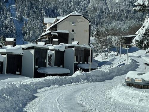 une maison est couverte de neige à côté d'une route dans l'établissement Studio 35m² pour 5 pers. avec balcon, centre station, proche commerces et pistes, animaux acceptés. - FR-1-787-61, à Laveissière