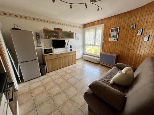 un salon avec un canapé et une cuisine dans l'établissement Studio au pied des pistes avec Wifi, idéal pour 4 personnes, proche commerces et patinoire - FR-1-787-63, à Laveissière