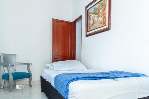 a bedroom with a bed and a chair and a picture at Casa Hotel Victoria Real in Mariquita