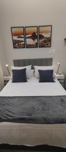 a bedroom with a large bed with four pictures on the wall at Maravilloso Apartamento Copacabana in Rio de Janeiro