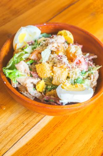 a bowl of salad with an egg on a wooden table at La Bella - Hotel Villa & Spa in Gili Trawangan