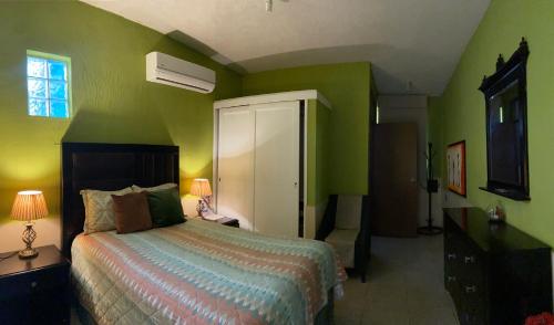 a bedroom with a bed and a green wall at Casa La Castañeda in Loreto