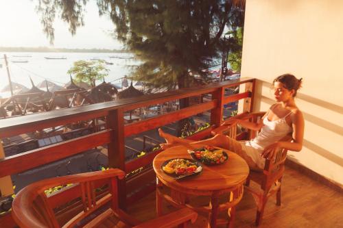 a woman sitting at a table with a plate of food at La Bella - Hotel Villa & Spa in Gili Trawangan
