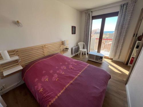 - une chambre avec un lit violet et une grande fenêtre dans l'établissement T2 avec climatisation, balcon vue mer, 250m de la plage - FR-1-701-83, à Valras-Plage