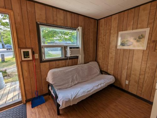 a small room with a bed and a window at Tiny Wood Cottage 17 in Wasaga Beach