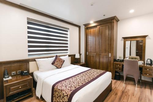 a hotel room with a bed and a desk and a chair at Menrva Hotel in Hai Phong