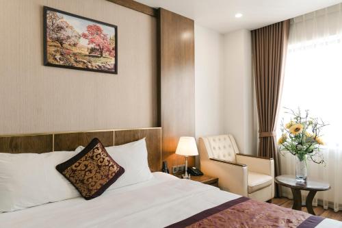a hotel room with a bed and a chair at Menrva Hotel in Hai Phong