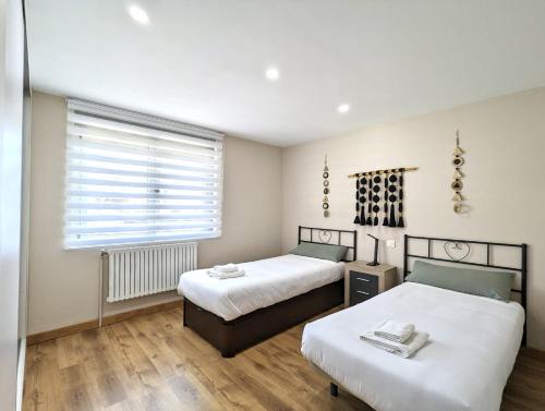 ein Schlafzimmer mit zwei Betten und einem Fenster in der Unterkunft Casa moderno en Renedo de Pielagos in Renedo de Piélagos