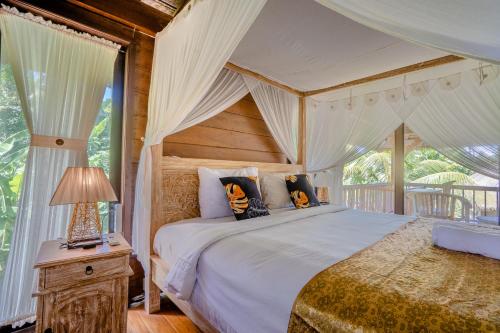 a bedroom with a canopy bed and a table with a lamp at Ubud Sawah Scenery Villa and Homestay in Tegalalang