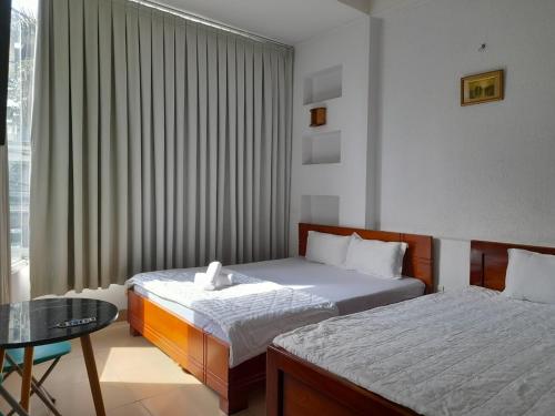 a bedroom with two beds and a table and a window at Khách sạn Mai Hoàng 2 in Ho Chi Minh City