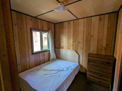 een kleine slaapkamer met een bed en een raam bij Tiny Wood Cottage 21 in Wasaga Beach